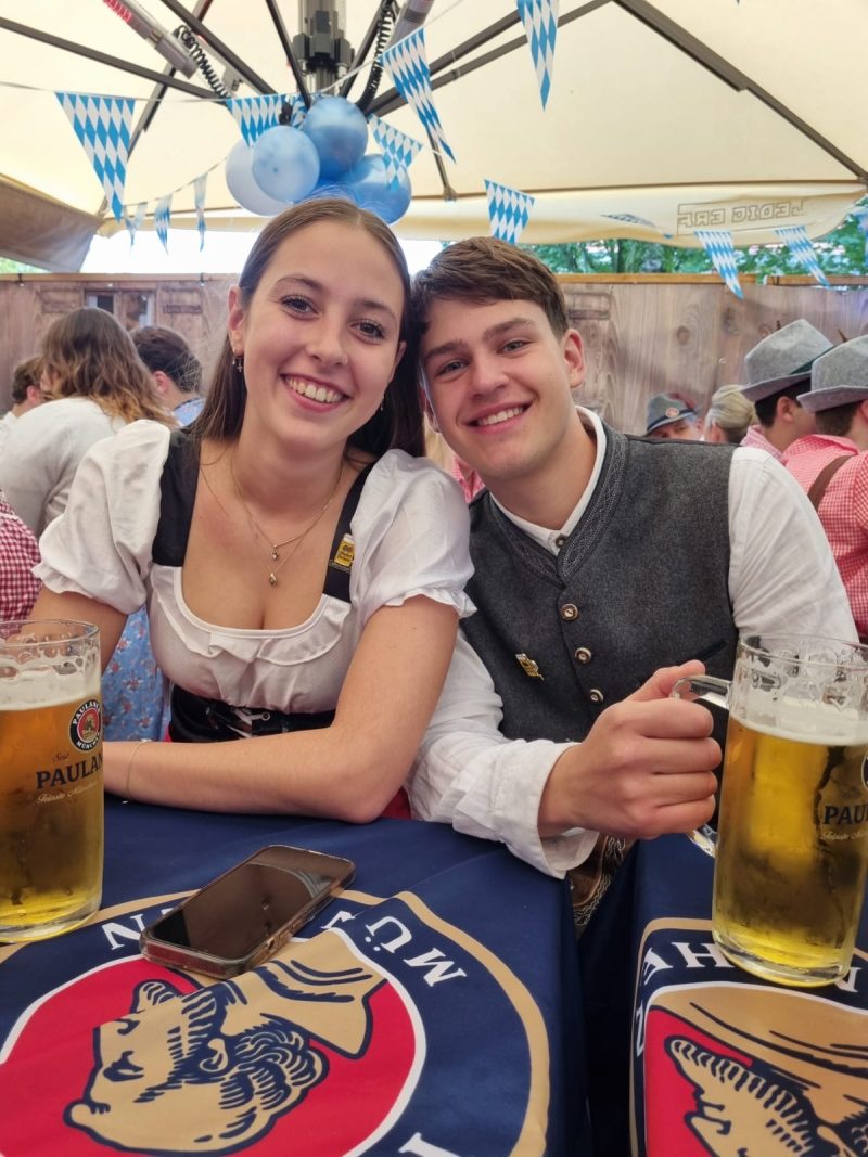 Gasten in dirndl en gilet aan de Paulaner-tafel
